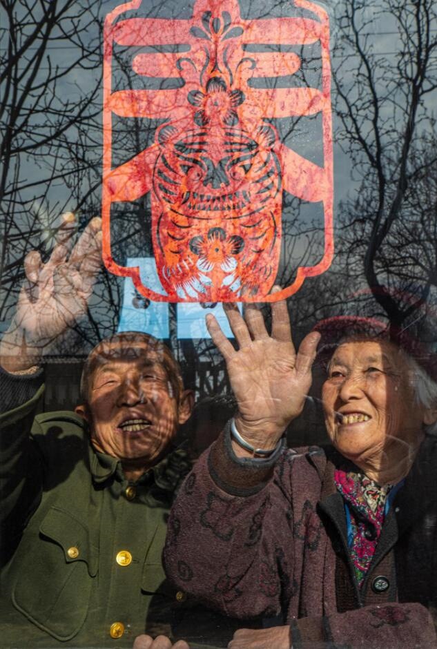 臘月里，霍州市師莊鄉(xiāng)馮南垣村村民師榮光(左)在災(zāi)后重建的新家里貼窗花。(霍州市委宣傳部供圖)