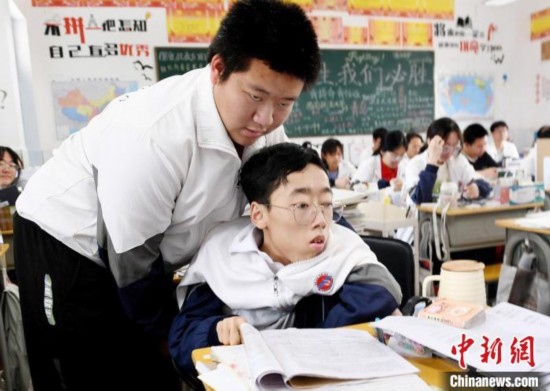朱金祥(左)把鐘華強放到課堂座位上后，都要把他擺正好，確認安全后才回到自己的座位上。 卓忠偉 攝