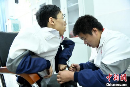 江西省南康中學北校區(qū)的高三學生朱金祥(右)正在給鐘華強(左)系好鞋帶。 卓忠偉 攝