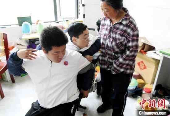 江西省南康中學北校區(qū)的高三學生朱金祥(左)來到學校給鐘華強母子安排的公寓，準備背他去課堂上課。 卓忠偉 攝