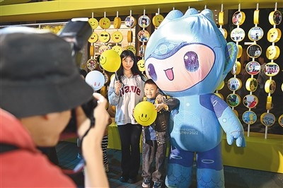 5月7日，在浙江省杭州市湖濱步行街“3D笑臉墻”前，攝影師為游客與杭州亞運(yùn)會吉祥物之一“宸宸”拍攝合影。