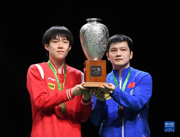 5月27日，樊振東（右）/王楚欽在頒獎儀式上高舉獎杯慶祝。當日，在南非德班進行的2023年世界乒乓球錦標賽男雙決賽中，中國組合樊振東/王楚欽以3比0戰(zhàn)勝韓國組合張禹珍/林鐘勛，奪得冠軍。新華社記者 李亞輝攝