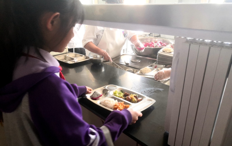 伊金霍洛旗第一小學(xué)學(xué)生正在打飯，今天的飯菜是三菜一湯外加水果，學(xué)生可以多次盛取，吃飽為止。人民網(wǎng)記者 孫博洋攝