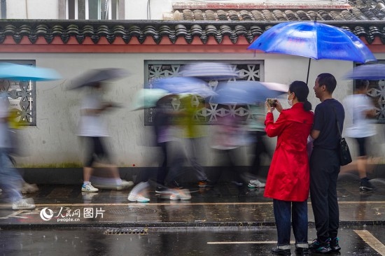 6月7日，在浙江省2023年普通高校招生考試鎮(zhèn)海中學(xué)考點(diǎn)，家長(zhǎng)冒雨目送子女進(jìn)入考場(chǎng)。人民網(wǎng) 章勇濤攝