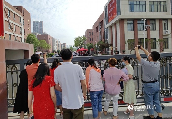 6月7日，武漢市第三中學(xué)考點(diǎn)，考生進(jìn)場(chǎng)后，家長(zhǎng)在柵欄外用手機(jī)拍攝自己的孩子。人民網(wǎng)記者 郭婷婷攝