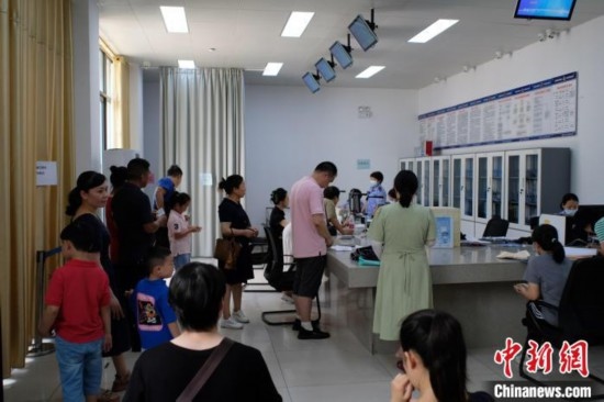 圖為在戶籍辦證廳內(nèi)排隊(duì)等待的家長和孩子。劉俊聰 攝