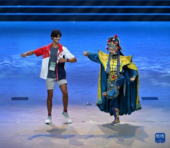 7月29日，美國運動員杜恩（左）在聯(lián)歡會現(xiàn)場與川劇演員互動。新華社記者 蔡湘鑫 攝