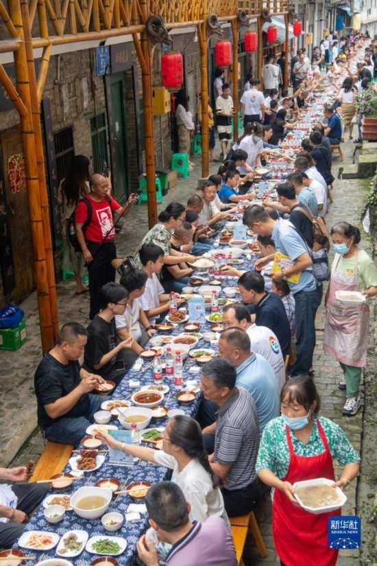7月29日，在重慶市綦江區(qū)安穩(wěn)鎮(zhèn)，人們?cè)凇懊缂曳蚬?jié)”上吃長(zhǎng)桌宴。新華社記者 唐奕 攝