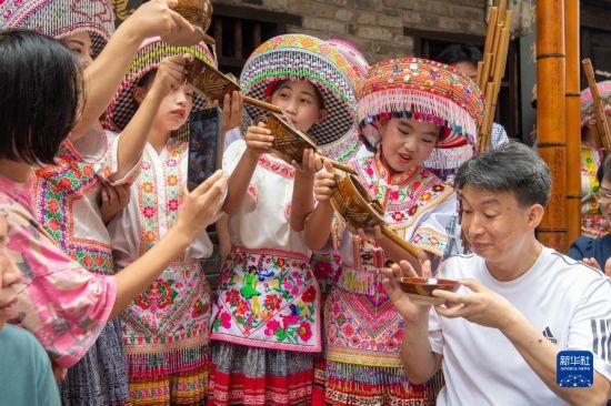 7月29日，在重慶市綦江區(qū)安穩(wěn)鎮(zhèn)，當(dāng)?shù)鼐用裨凇懊缂曳蚬?jié)”上用傳統(tǒng)習(xí)俗向游客表達(dá)祝福。新華社記者 唐奕 攝
