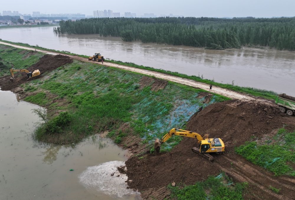 工人操作機(jī)械在白溝河左堤白溝新城高橋村段進(jìn)行除險(xiǎn)加固作業(yè)（8月4日攝，無(wú)人機(jī)照片）。新華社記者 朱旭東 攝