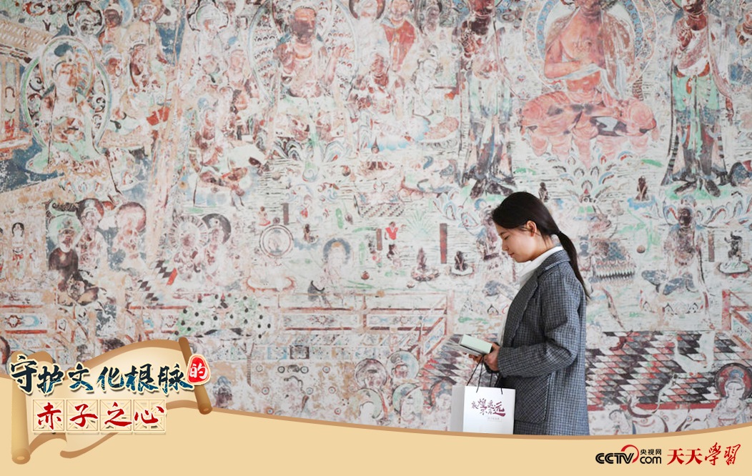 2023年4月25日，敦煌研究院文物數(shù)字化保護(hù)團(tuán)隊創(chuàng)意營銷人員廖雪婷從一幅高保真復(fù)制壁畫前走過。