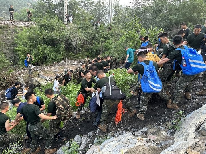 8月2日，Z180次受困列車的旅客在武警北京總隊(duì)機(jī)動(dòng)第三支隊(duì)官兵的幫助下徒步前往轉(zhuǎn)運(yùn)客車（手機(jī)照片）。新華社記者 王艷剛 攝