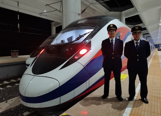 劉銀能（右一）與中國師父鄔俊鴻在動車組前合影。受訪者供圖