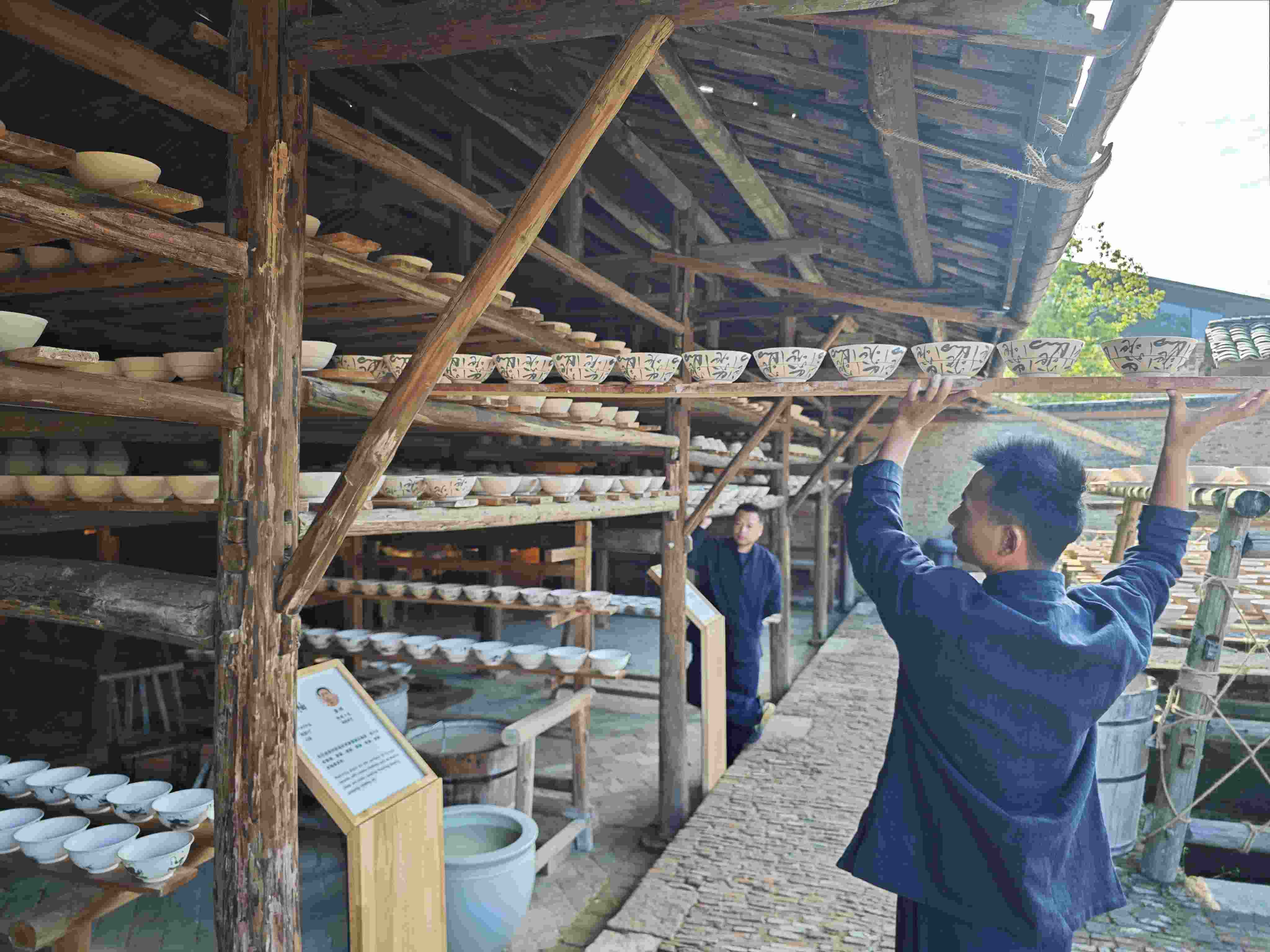 △陶陽里歷史文化街區(qū)里，工匠將陶瓷工藝品放到架上晾干。（總臺央視記者彭漢明拍攝）