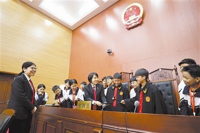 圖③：同學(xué)們穿法袍、敲法槌，爭做“小法官”。
