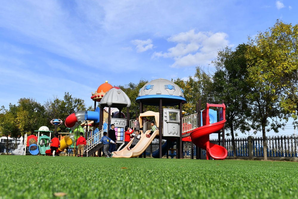 在山東省東營市墾利區(qū)楊廟社區(qū)幼兒園，孩子們在老師的帶領(lǐng)下進行戶外活動（2021年10月19日攝）。新華社記者 郭緒雷 攝