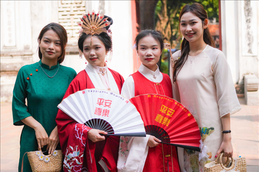 身穿古裝的中國(guó)游客和身穿越南傳統(tǒng)服飾奧黛的越南青年在文廟門(mén)前合影。