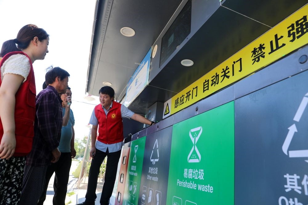 在安徽省合肥市長豐縣莊墓鎮(zhèn)棗林社區(qū)，志愿者指導居民使用智能垃圾分類回收設(shè)備（2023年9月1日攝）。新華社記者 曹力 攝