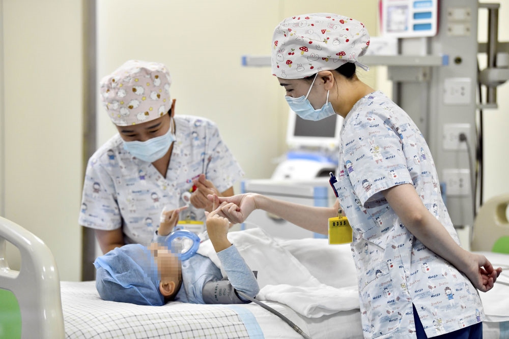 在山東省棗莊市婦幼保健院兒童ICU病房，醫(yī)護人員為完成靶向治療藥物諾西那生鈉的4歲脊髓性肌萎縮癥患兒加油鼓勁（2022年1月1日攝）。諾西那生鈉注射液是我國首個獲批治療脊髓性肌萎縮癥的進口藥物，2019年進入中國市場時，每針價格近70萬元。在2021年國家醫(yī)保目錄藥品談判中，以3.3萬元每針的價格進入新版醫(yī)保藥品目錄。新華社記者 郭緒雷 攝