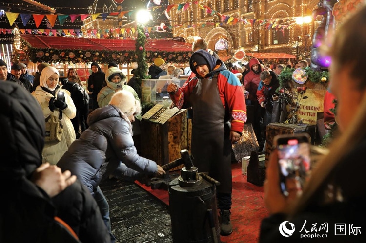 游客在新年集市上體驗制作紀(jì)念幣。人民網(wǎng)記者 隋鑫攝
