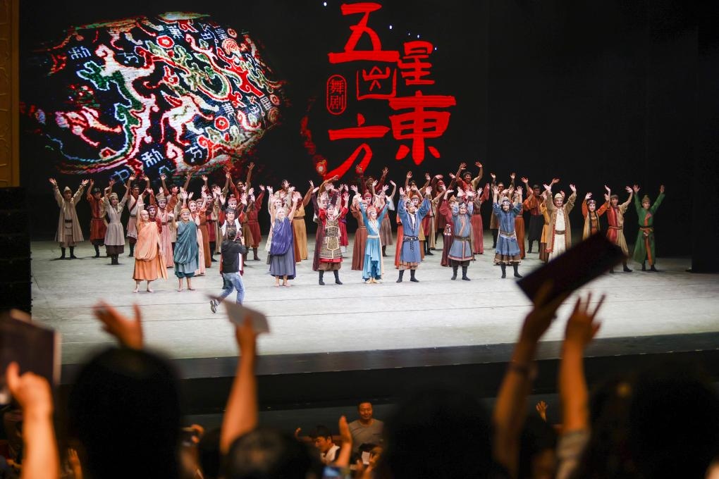 2023年7月31日，新疆和田地區(qū)新玉歌舞團(tuán)在烏魯木齊京劇院演出舞劇《五星出東方》后和觀眾互相揮手致意。這場演出是第六屆中國新疆國際民族舞蹈節(jié)的參演劇目之一，曾榮獲國家“文華獎(jiǎng)”等。新華社記者 郝昭 攝