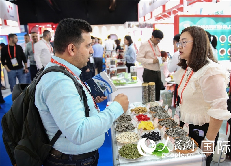圖為一家中國(guó)干果參展企業(yè)代表與采購(gòu)商洽談。人民網(wǎng) 塔里克·易卜拉欣攝