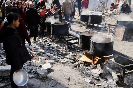  2月27日，在加沙地帶北部的杰巴利耶難民營，人們等待領取食物。新華社發(fā)（穆罕默德·阿里攝）