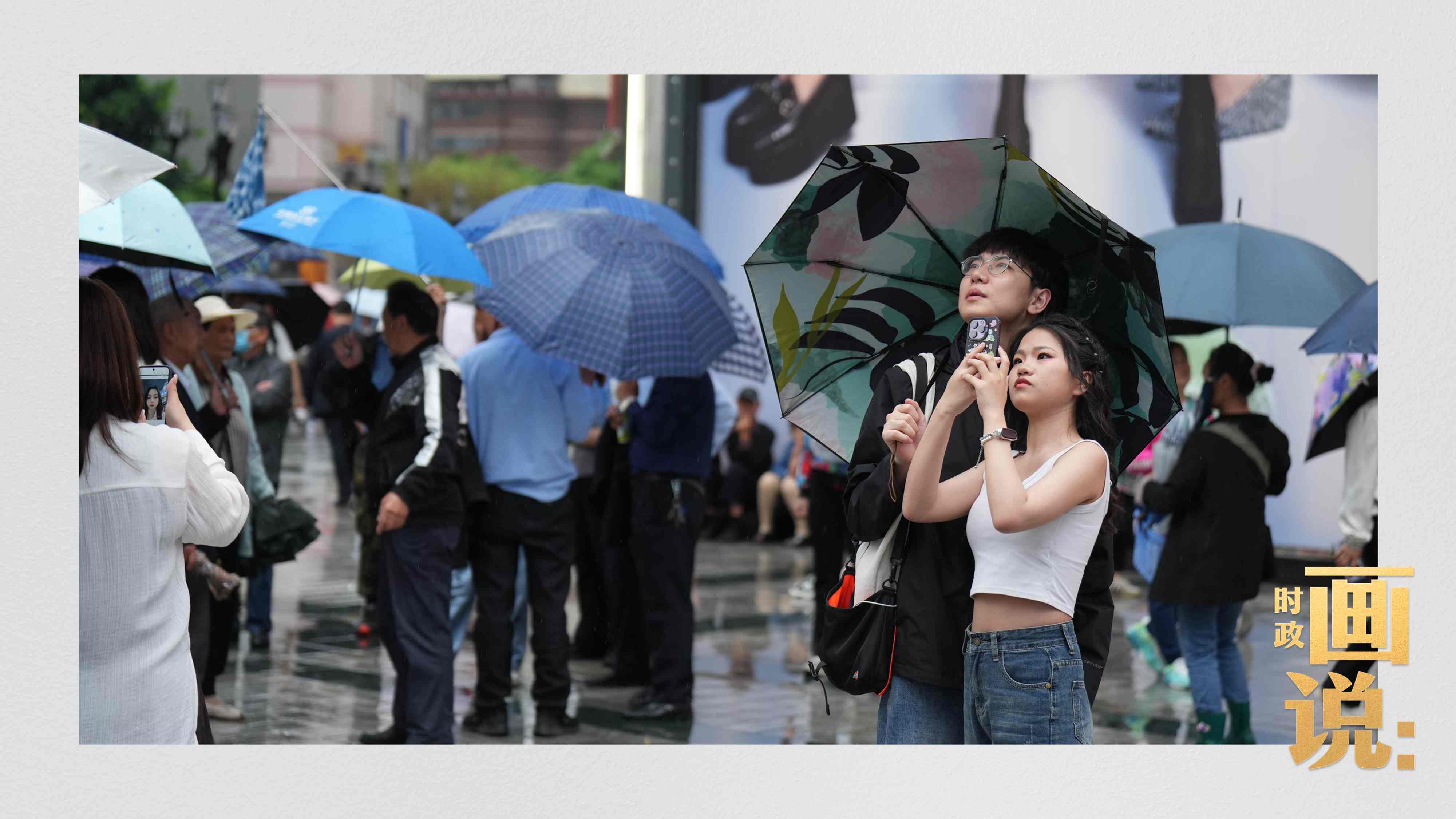 △細(xì)雨中的解放碑步行街，騎在父親肩膀的小女孩好奇張望。