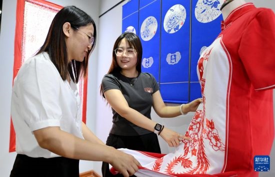 5月31日，在衡水市阜城縣一家剪紙工作室，游客在觀賞帶有剪紙?jiān)氐钠炫邸? width=