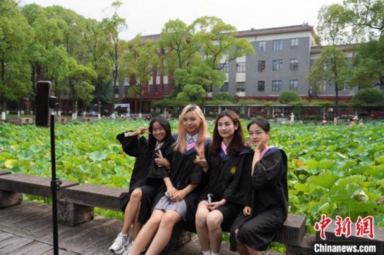 6月19日，時(shí)值一年畢業(yè)季，四川大學(xué)望江校區(qū)荷花池里的荷花盛開(kāi)，成為了畢業(yè)生們的打卡圣地，吸引了眾多畢業(yè)生拍照留念。圖為畢業(yè)生在荷花池邊拍照留念。中新社記者 安源 攝