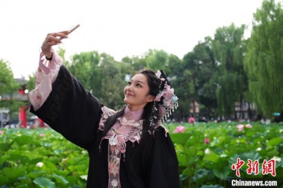 6月19日，時(shí)值一年畢業(yè)季，四川大學(xué)望江校區(qū)荷花池里的荷花盛開(kāi)，成為了畢業(yè)生們的打卡圣地，吸引了眾多畢業(yè)生拍照留念。圖為畢業(yè)生在荷花池邊拍照留念。中新社記者 安源 攝