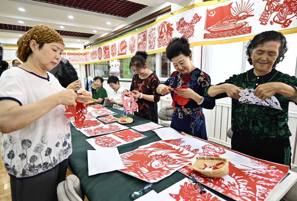 6月19日，長城花園社區(qū)居民在社區(qū)“才藝堂”制作剪紙。