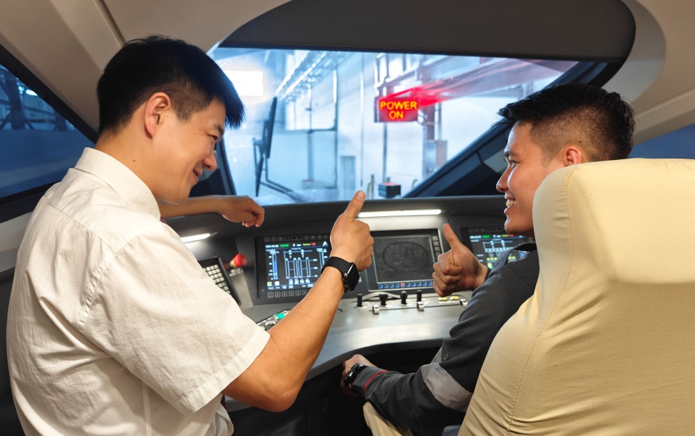 2023年8月25日，在印度尼西亞萬隆的雅萬高鐵德卡魯爾動車所內(nèi)，中國師傅穆振（左）向印尼火車司機塞蒂亞萬講解動車組出庫前的上電作業(yè)。新華社記者 徐欽 攝