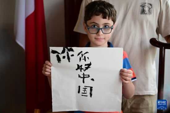 7月4日，在馬耳他桑塔露琪亞市的中國古典園林“靜園”，一名男孩展示他的書法作品。新華社發(fā)（喬納森·博格 攝）