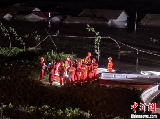  7月6日凌晨3時(shí)，在湖南岳陽(yáng)華容縣團(tuán)洲垸洞庭湖一線堤防，救援人員剛剛完成一次救援任務(wù)，遠(yuǎn)處是被淹的民房。中新社記者 白祖偕 攝
