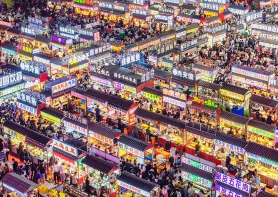 2024年4月21日，人們?cè)诤颖笔≌h小商品夜市品嘗美食（無(wú)人機(jī)照片）。新華社發(fā)（武志偉 攝）