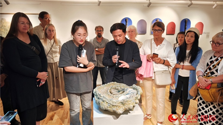 參展人、景德鎮(zhèn)陶瓷大學(xué)設(shè)計藝術(shù)學(xué)院副院長余劍峰（中）向來賓介紹參展作品。人民網(wǎng)記者 殷淼攝