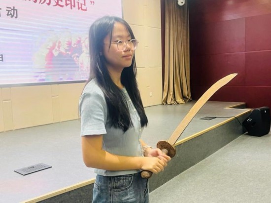 圖為南開大學(xué)社會實踐隊學(xué)生代表呼月紅在學(xué)術(shù)交流活動現(xiàn)場，展示河間調(diào)研行中獲贈的一戰(zhàn)華工蔡世春曾使用過的一把大刀。林卓瑋 攝
