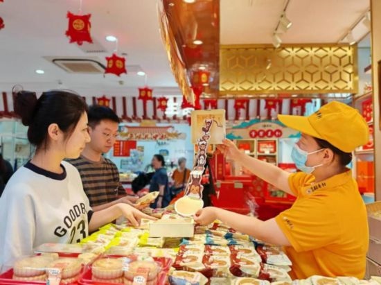 北京稻香村一家門店內(nèi)，售貨員向顧客展示新上市的月餅禮盒。（受訪者供圖）