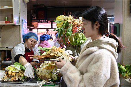 游客挑選好麻辣燙菜品后排隊等待加工。新華社記者 范培珅 攝