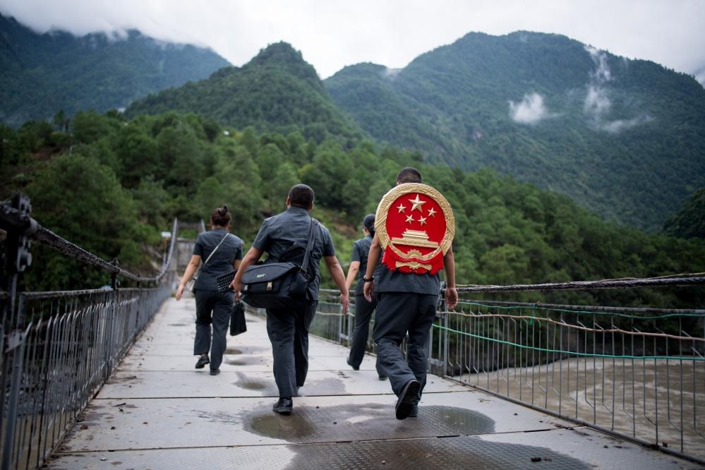 云南省怒江傈僳族自治州貢山縣人民法院法官鄧興背著國(guó)徽與同事們跨過(guò)怒江（2019年8月30日攝）。怒江高山峽谷眾多，交通不便，為方便群眾、更好地開(kāi)展法律服務(wù)，背著國(guó)徽攀高山、過(guò)索橋、躲落石、鉆老林……成為鄧興法官的工作常態(tài)。新華社記者 江文耀 攝