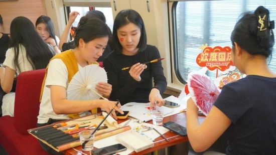 10月1日，旅客們在G1634次列車上給油紙傘作畫。新華社記者周義 攝