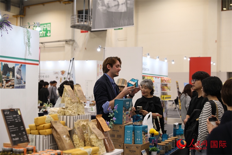 當(dāng)?shù)貢r間10月5日，在第21屆釜山國際美食博覽會上，意大利展商向參觀者們介紹的意大利食品。人民網(wǎng)記者 莽九晨攝