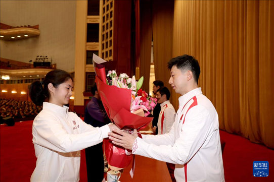 11月15日，一名學(xué)生代表在報(bào)告會(huì)上向乒乓球運(yùn)動(dòng)員馬龍（右）獻(xiàn)花。新華社記者 李明 攝