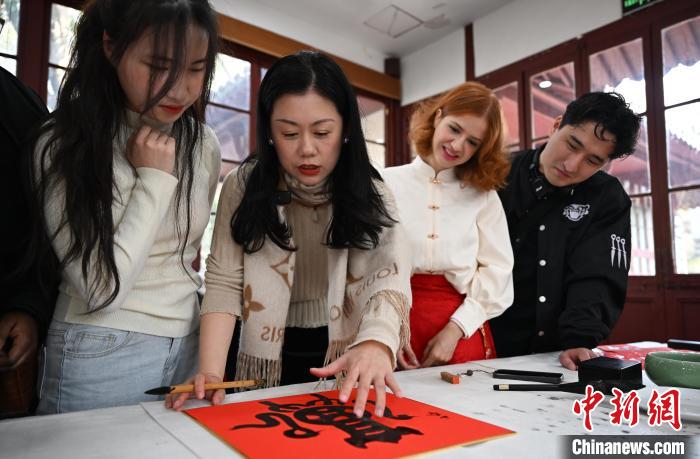 1月20日，西泠印社社員李硯（左二）為外籍留學(xué)生講述蛇年福字貼創(chuàng)作靈感。當(dāng)日，來自巴西、馬來西亞、加納、哈薩克斯坦的外籍留學(xué)生在浙江杭州西泠印社體驗福貼、春聯(lián)和篆刻，感受古老的中國傳統(tǒng)文化。中新社記者 王剛 攝