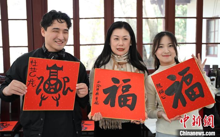 1月20日，外籍留學(xué)生和西泠印社社員李硯(中)展示各自創(chuàng)作的福貼。當(dāng)日，來自巴西、馬來西亞、加納、哈薩克斯坦的外籍留學(xué)生在浙江杭州西泠印社體驗福貼、春聯(lián)和篆刻，感受古老的中國傳統(tǒng)文化。中新社記者 王剛 攝