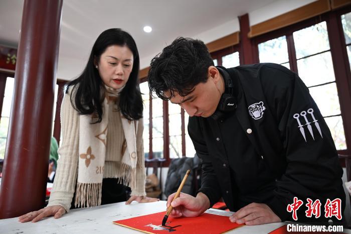 1月20日，外籍留學(xué)生在西泠印社社員李硯指導(dǎo)下寫福。當(dāng)日，來自巴西、馬來西亞、加納、哈薩克斯坦的外籍留學(xué)生在浙江杭州西泠印社體驗福貼、春聯(lián)和篆刻，感受古老的中國傳統(tǒng)文化。中新社記者 王剛 攝