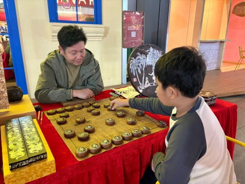 柯秋楓與市民下椰雕象棋。人民網(wǎng) 陳葉欣攝